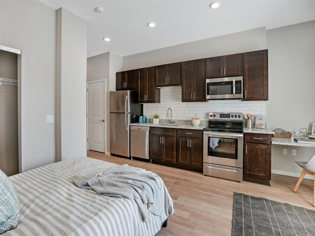 A modern kitchen with dark brown cabinets and stainless steel appliances.