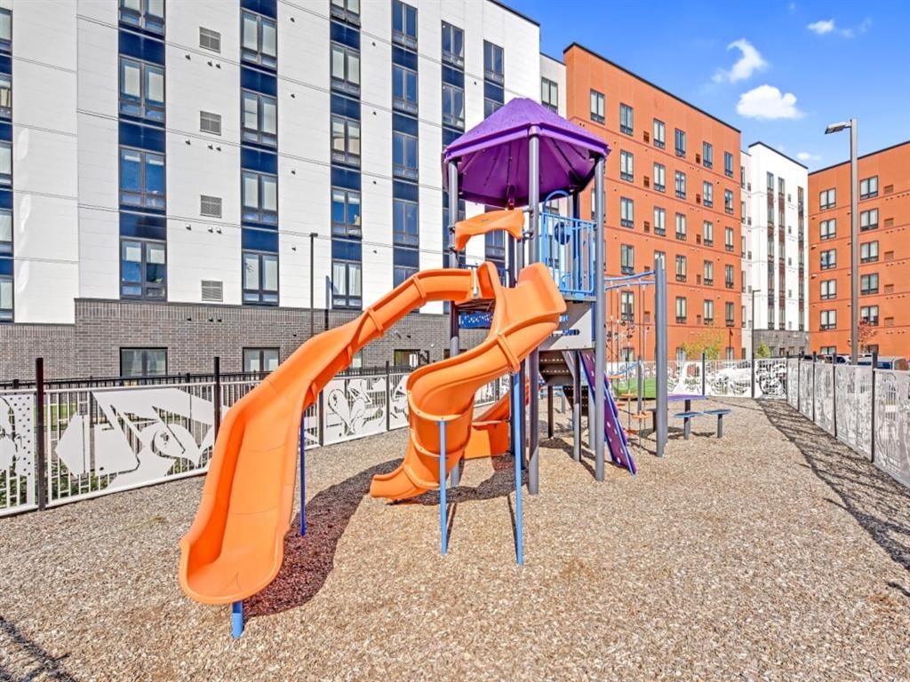 A playground with a purple slide and orange slide.