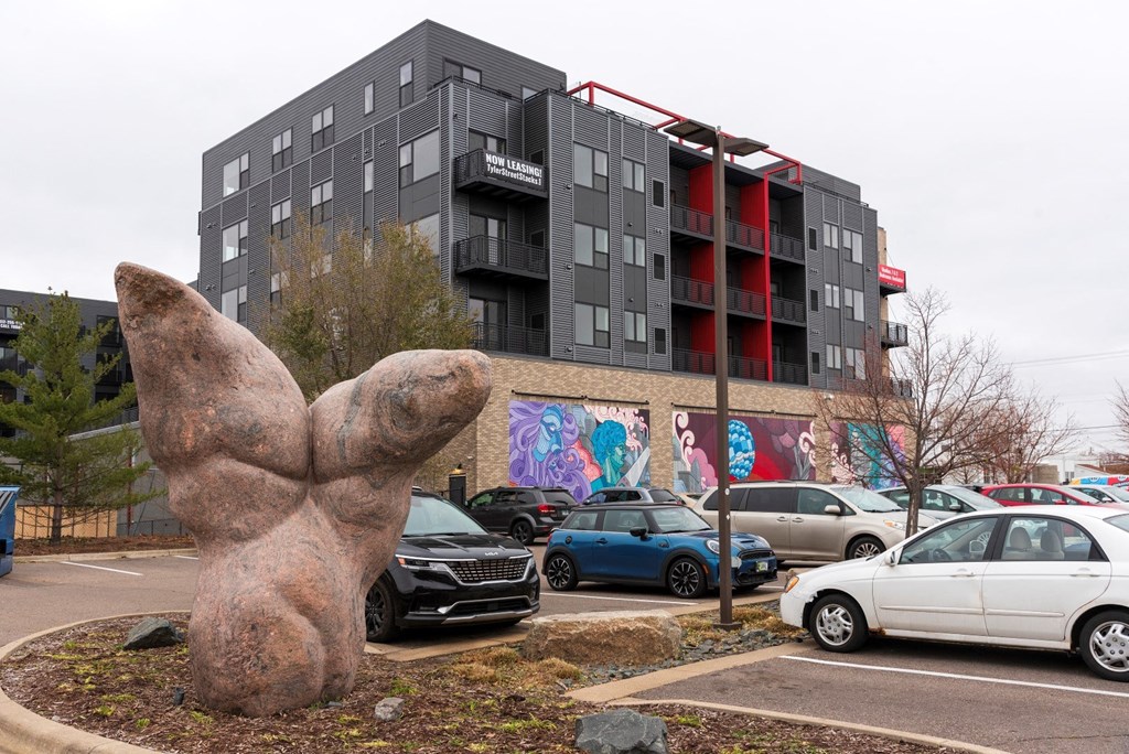 a statue of a hand in front of a parking lot with cars