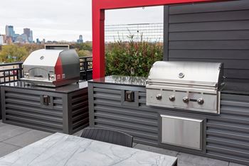 two bbqs on the patio of a home with a view of the city