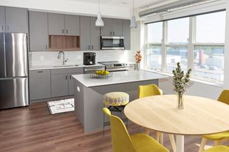 a kitchen with gray cabinets and a wooden table with yellow chairs