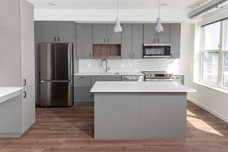 a kitchen with gray cabinets and white countertops