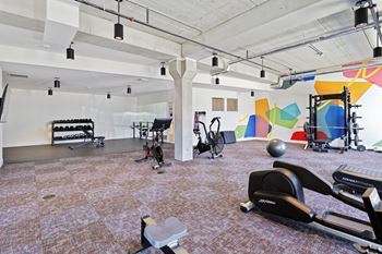 a gym with exercise equipment and paintings on the wall