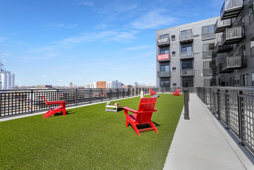 chairs on a roof terrace with grass and a view of the city