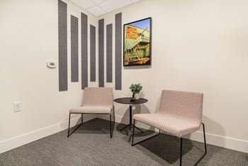 two chairs and a table in a room with a painting on the wall