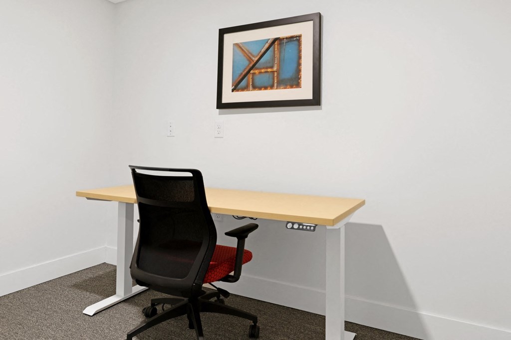 a desk with a chair and a picture on the wall
