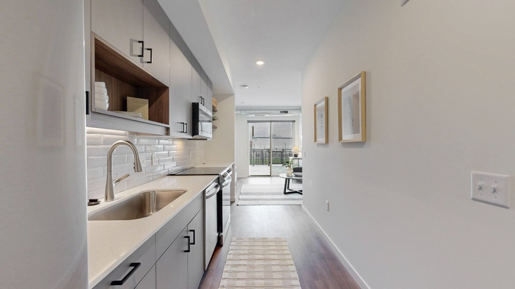 A modern kitchen with a white countertop and stainless steel appliances.