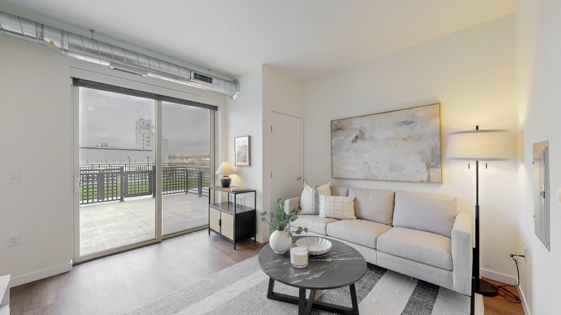 A living room with a grey couch, a coffee table, and a painting on the wall.