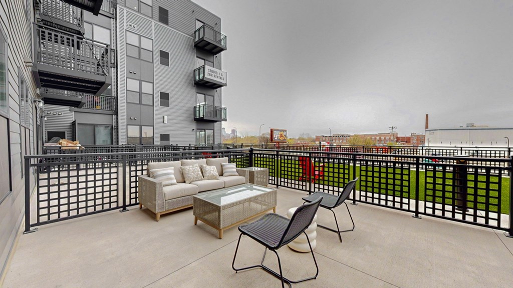 A balcony with a couch, chairs and a coffee table.