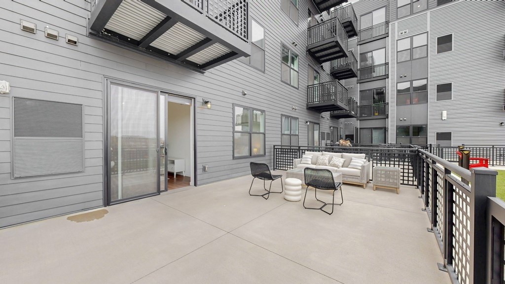 A patio area with a table and chairs is surrounded by a metal fence.