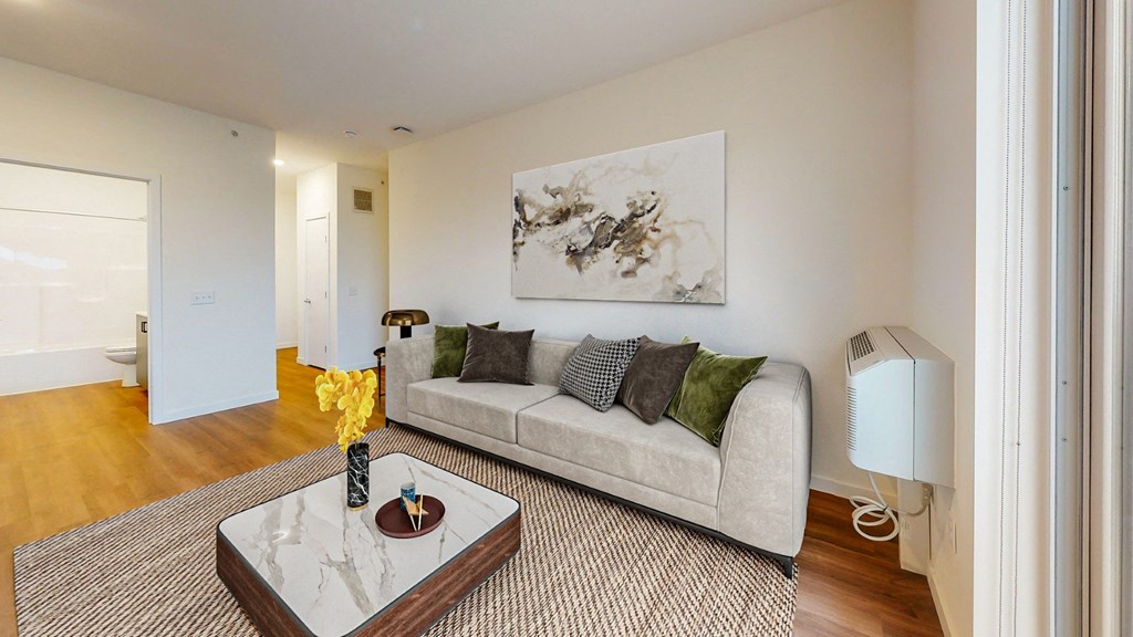 A living room with a couch, coffee table, and a painting on the wall.