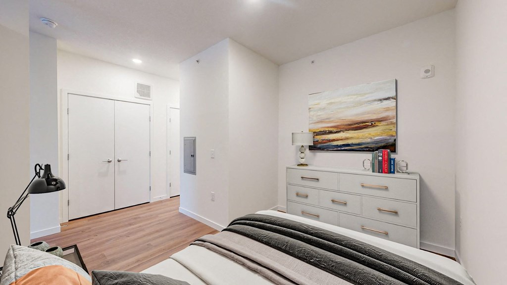 A bedroom with a bed, dresser, and painting on the wall.
