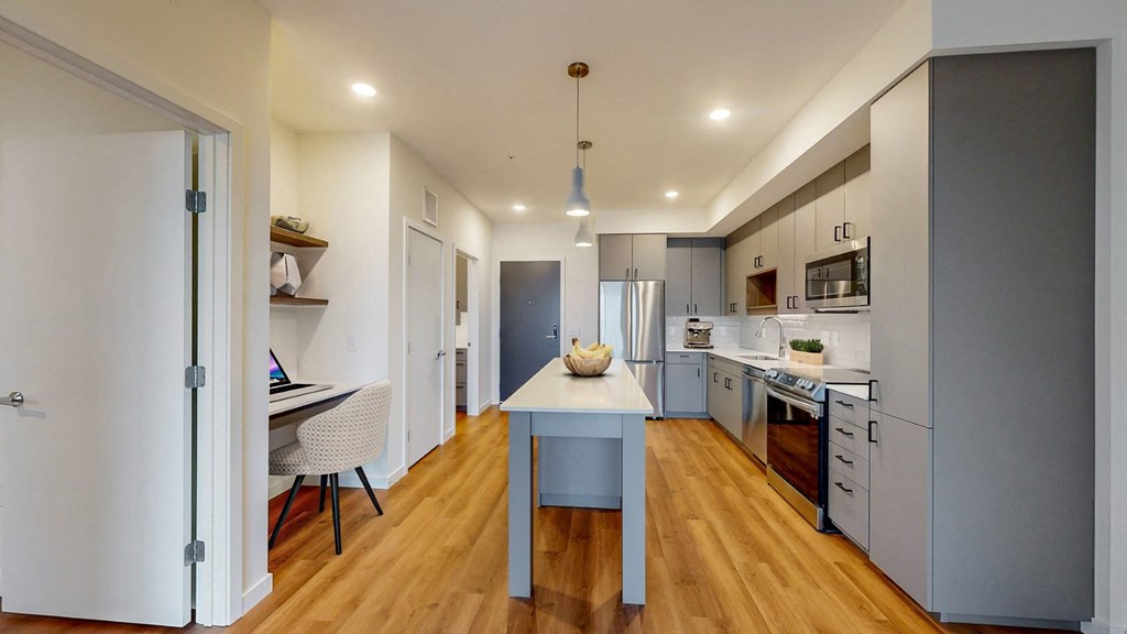A modern kitchen with a table and chairs in the middle.