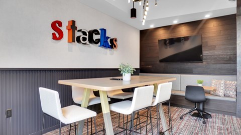 A conference room with a table, chairs, and a sign that says Stacks.