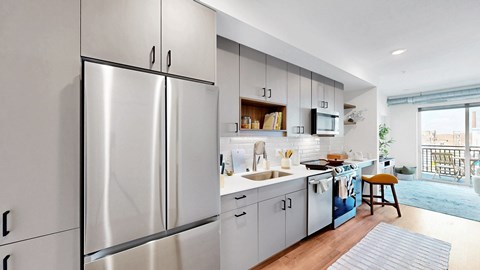 A modern kitchen with stainless steel appliances and a wooden floor.
