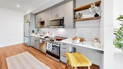 A modern kitchen with a yellow chair and white cabinets.