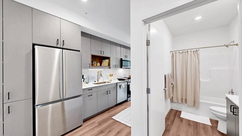 A modern kitchen with a refrigerator, cabinets, and a bathroom with a shower.