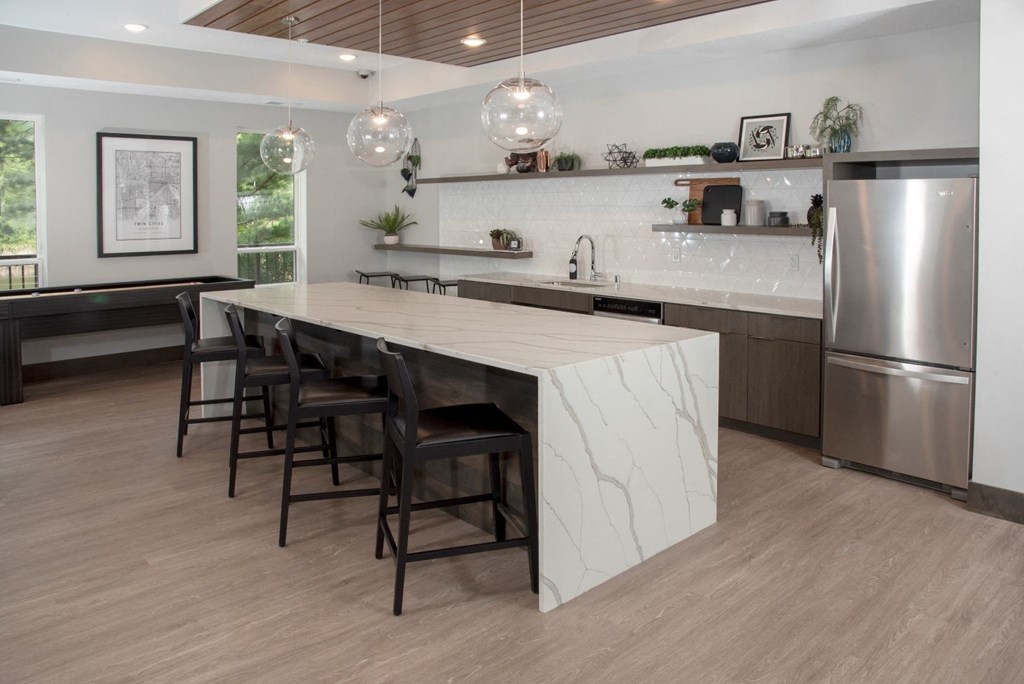Community kitchen with bar seating and shuffleboard table at Urban Park I and II Apartments, St Louis Park, 55426