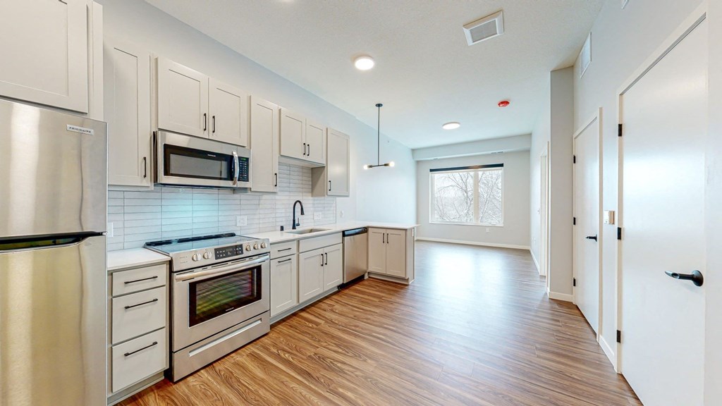 a kitchen with white cabinets and a wooden floor