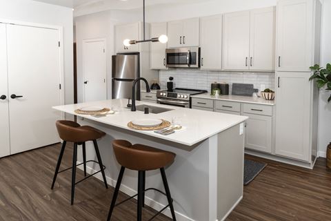 a kitchen with white cabinets and a white island with two stools