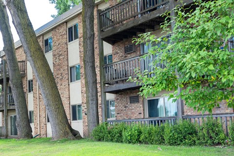 A building with a balcony and a tree in front of it.