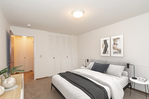A bedroom with a large bed and a nightstand with a lamp.