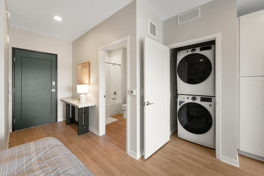 a bedroom with a washer and dryer in it and a bathroom with a