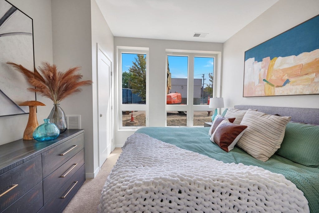 a bedroom with a bed and a dresser in front of a window