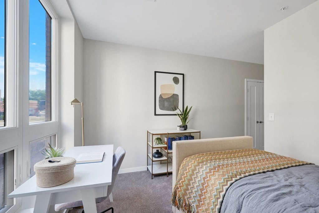 a bedroom with a large window and a desk with a chair