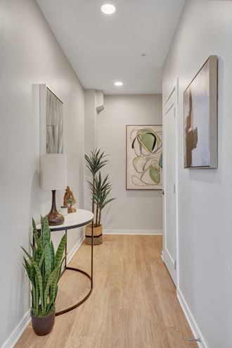 a hallway with white walls and a white table with a lamp on it