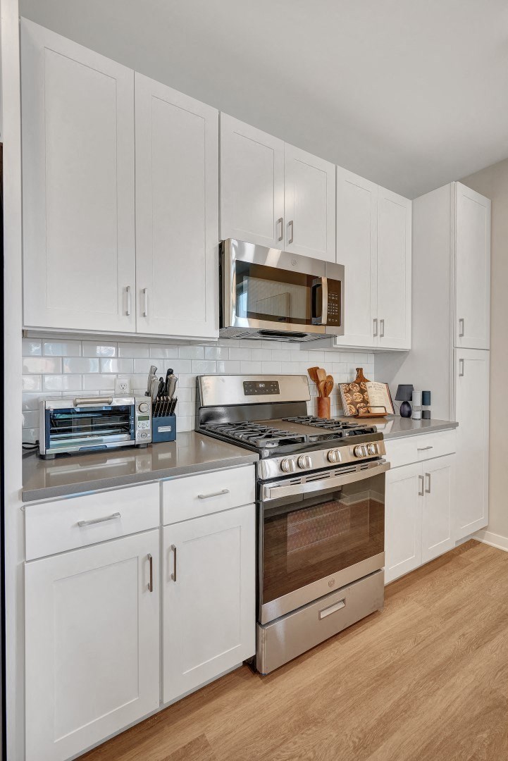 a kitchen with white cabinets and stainless steel appliances