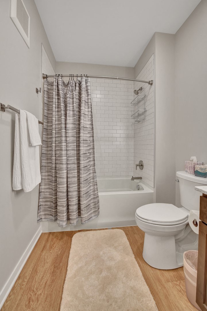 a bathroom with a white toilet next to a bathtub with a shower curtain