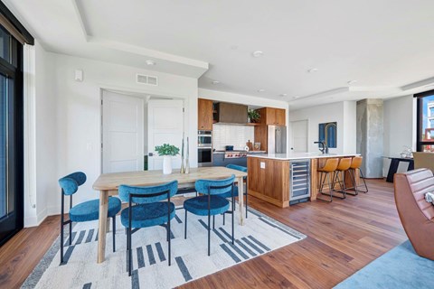 a dining area with a table and chairs and a kitchen in the background