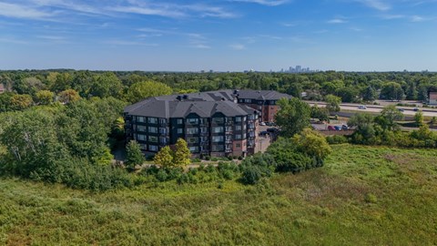 A large building with a black roof is surrounded by greenery.