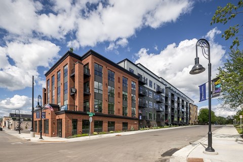 A street view of a building with a blue sky and clouds in the background.