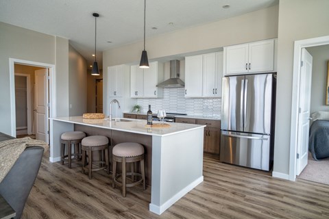 A kitchen with a white counter and stools.