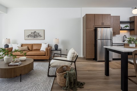 A modern living room with a brown sofa, a coffee table, and a dining table.