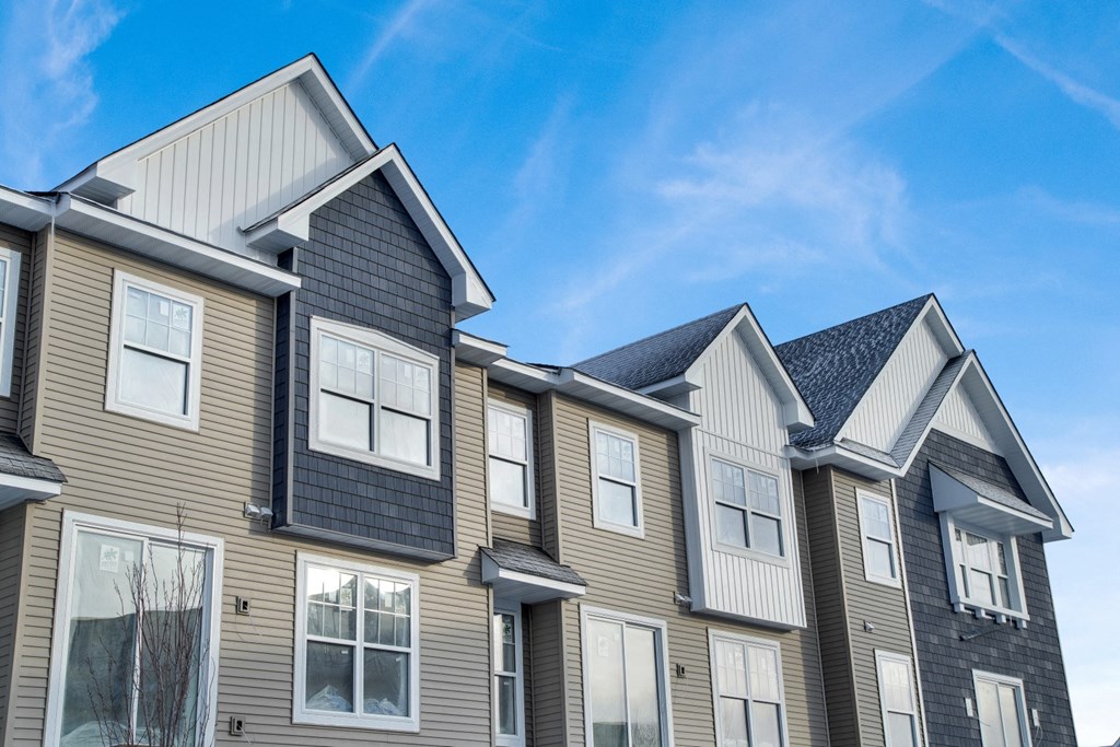 a row of houses with siding and a blue sky