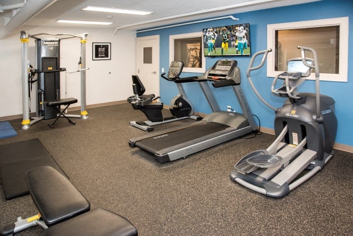 a gym with cardio equipment and a flat screen tv