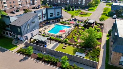 A pool surrounded by a grassy area and a building.