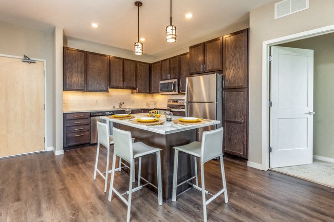a kitchen with a center island with white chairs