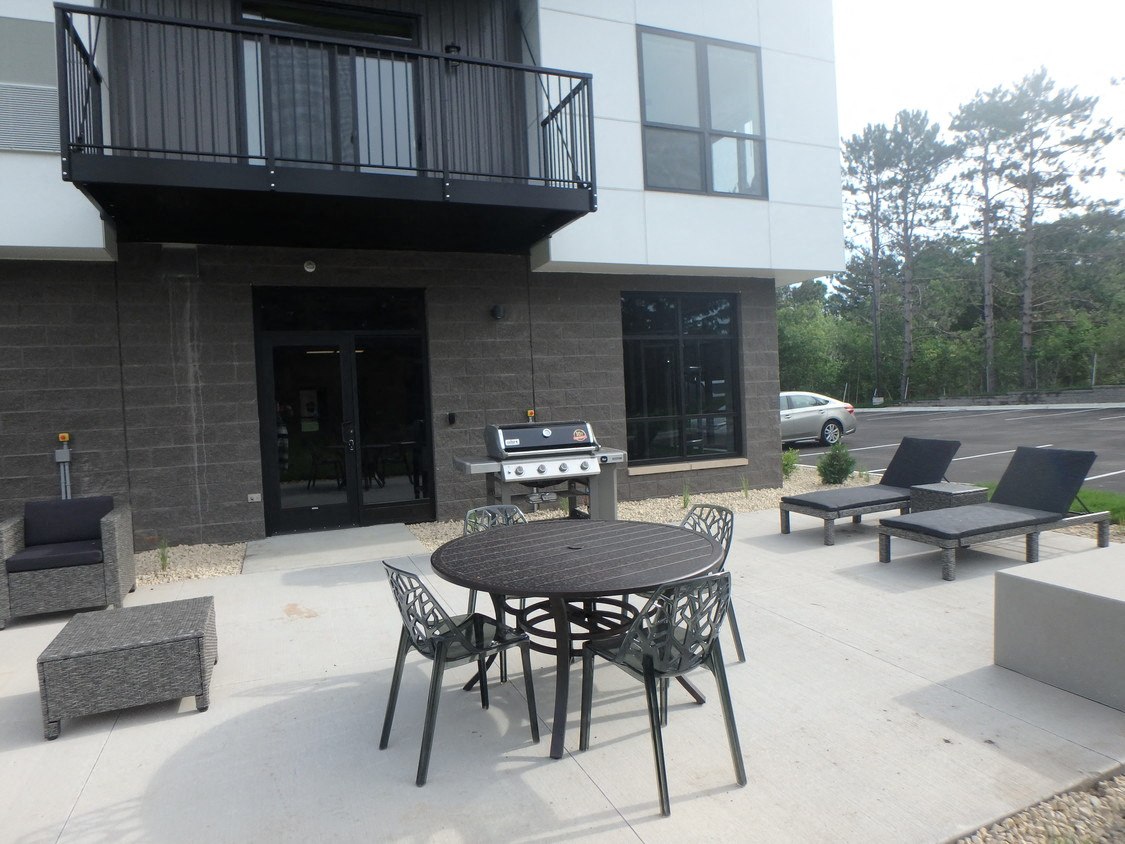 a patio with a table and chairs and a grill