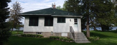 a small white house with stairs and a green roof