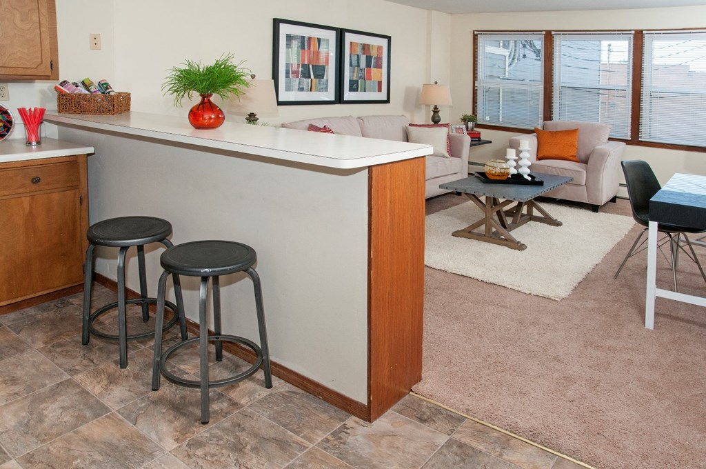 a kitchen and living room with a bar and stools