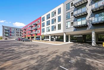 A parking lot in front of a multi-story building with cars parked.
