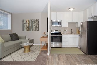 a small living room with a couch and a coffee table next to a kitchen with a stove