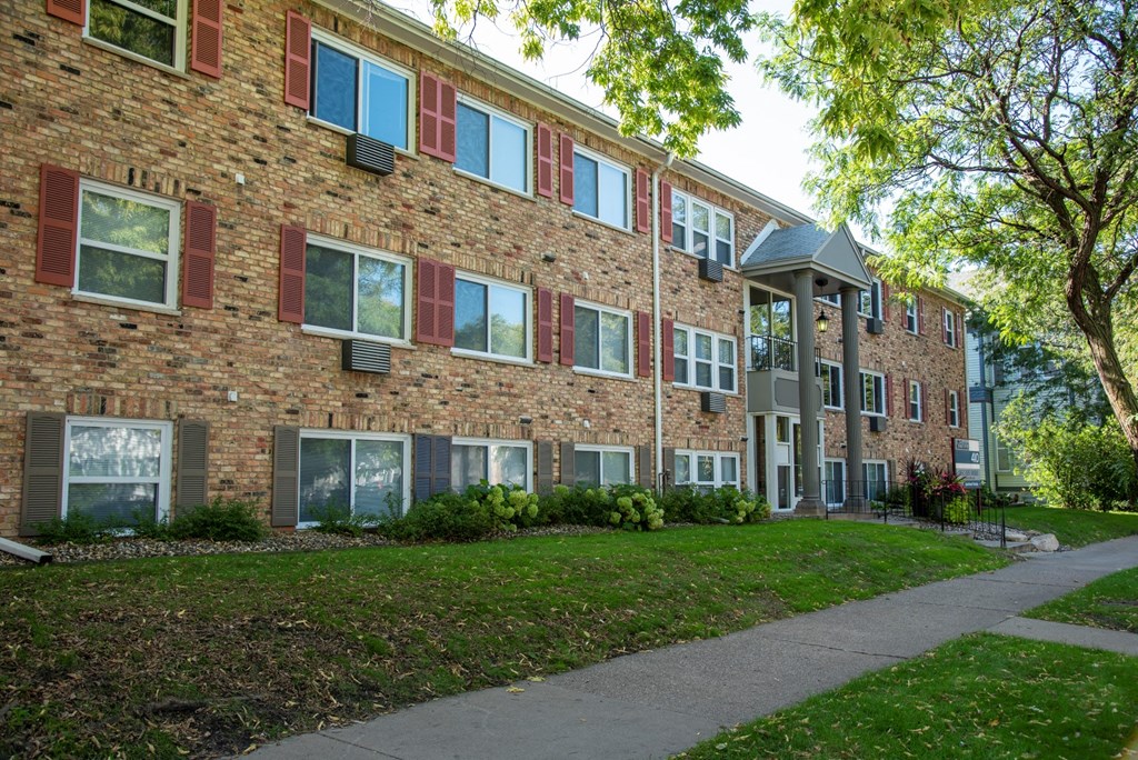 a brick apartment building with a sidewalk in front of it