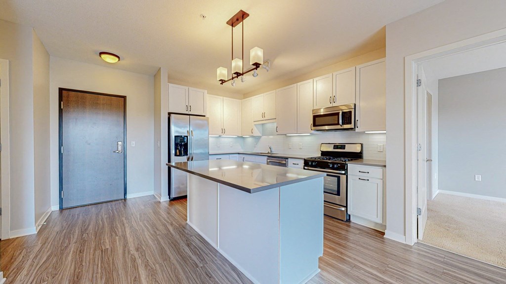 A kitchen with white cabinets and a wooden floor.