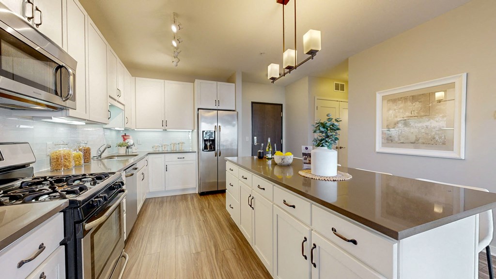 A modern kitchen with white cabinets and stainless steel appliances.