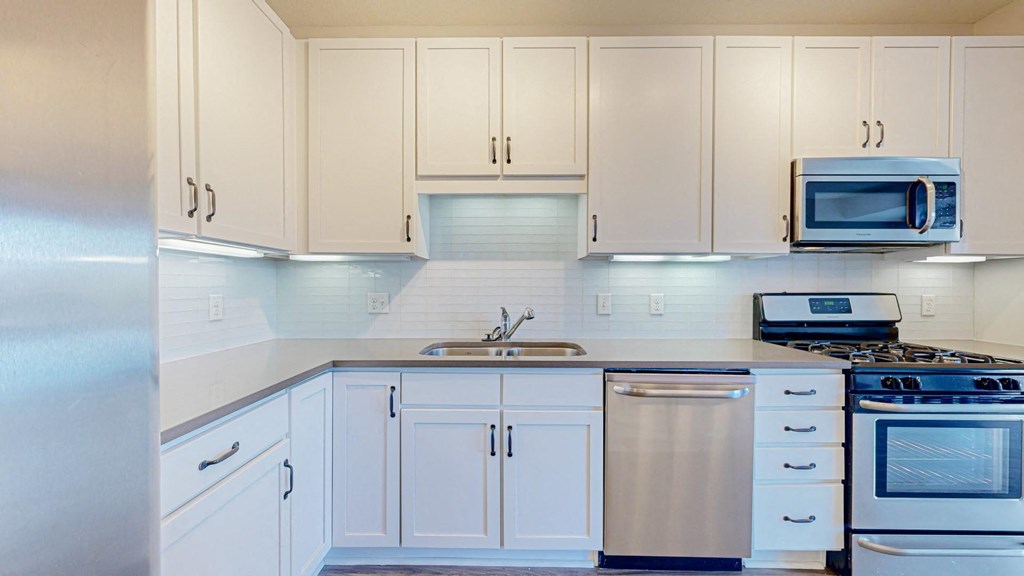 A kitchen with white cabinets and appliances.